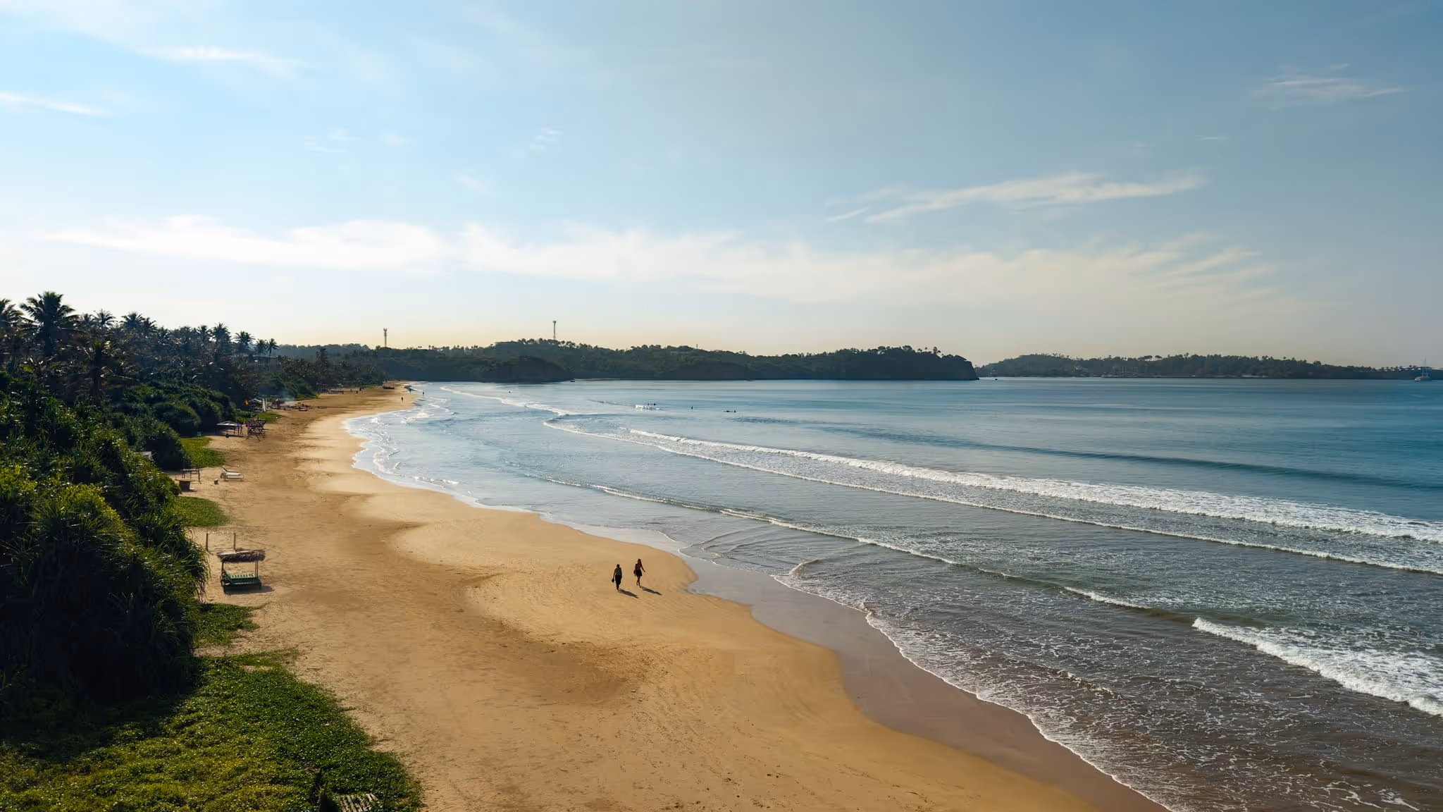 Weligama Bay with sandy beaches, surfing waves, and coconut palms